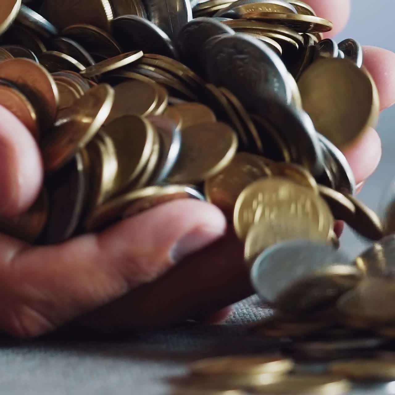 Close up gold and silver coins in hand. Slow motion.