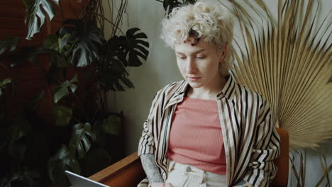 young woman using laptop in room with monstera plant