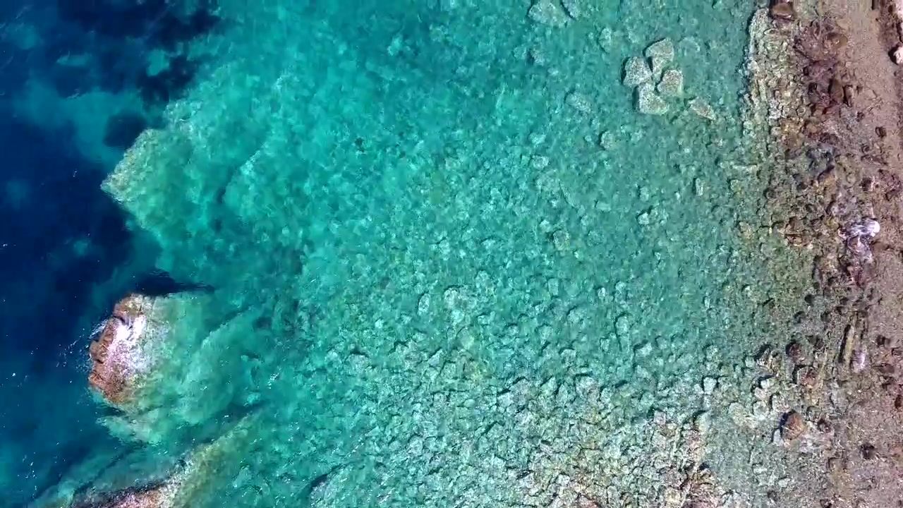 Flygfoto över klart turkost vatten och klippig kustlinje