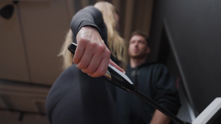 Extreme low-angle close-up focuses on a woman's hand gripping an electrode handle during a body composition test.