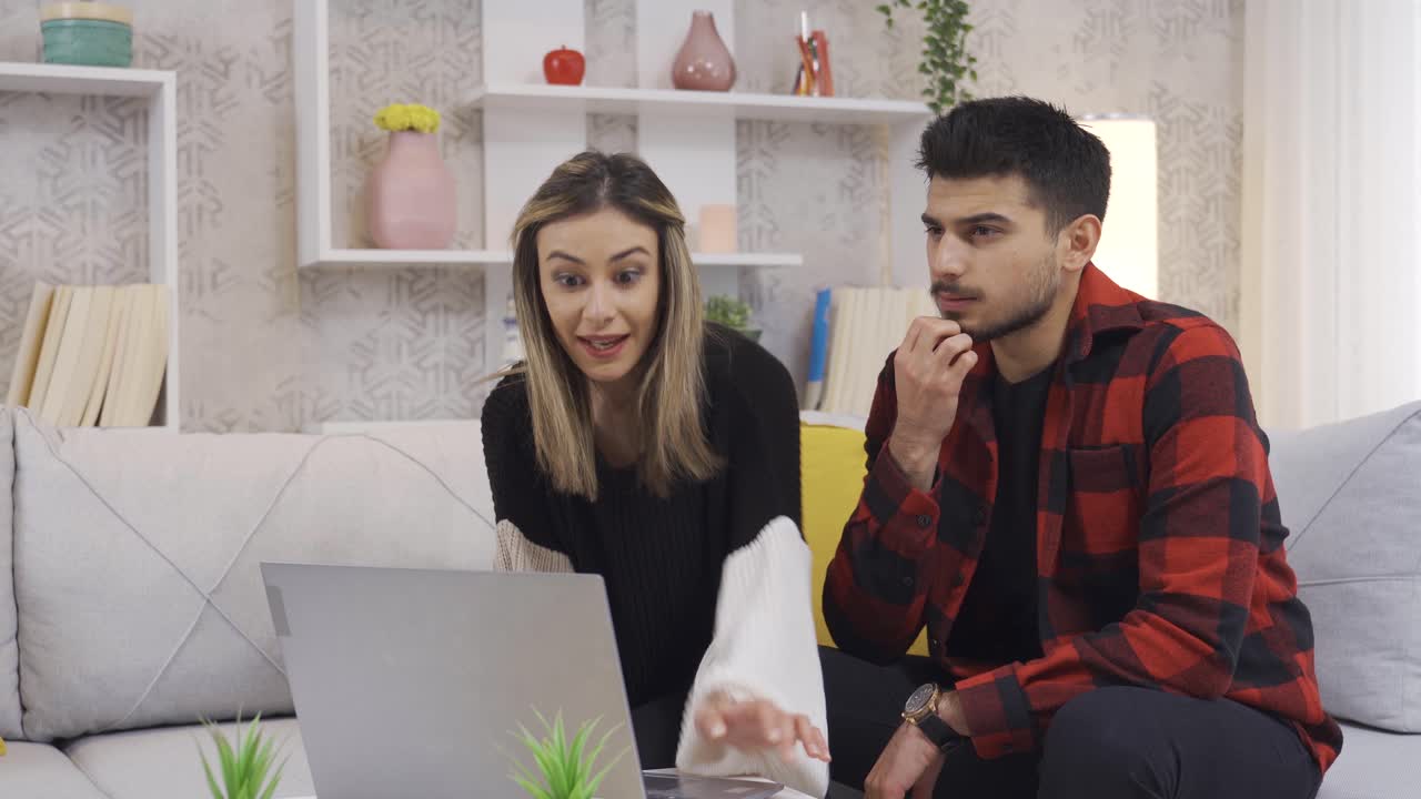 una feliz pareja casada usando una computadora portátil en casa.