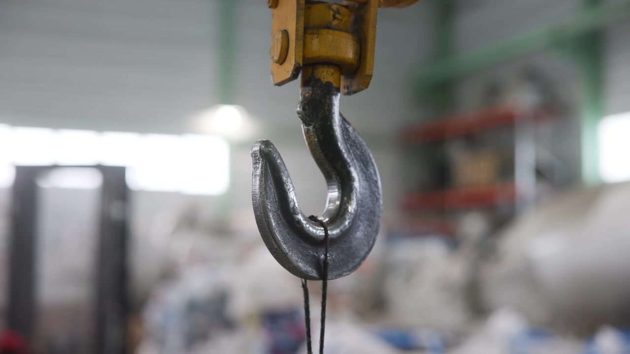 Gancio di sollevamento in acciaio pesante appeso in un'officina industriale. Filmato 4K di alta qualità.