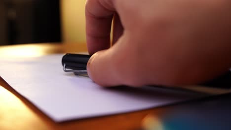 a-fine-black-fountain-pen-is-placed-by-one-hand-on-paper-on-a-desk-and-again