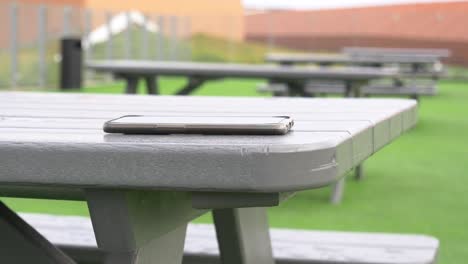 a black smartphone is laying on a gray picnic table