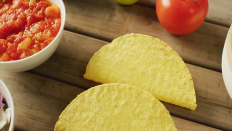 Video-Von-Tacos,-Passata,-Tomaten-Und-Anderen-Zutaten,-Die-Auf-Holzhintergrund-Liegen