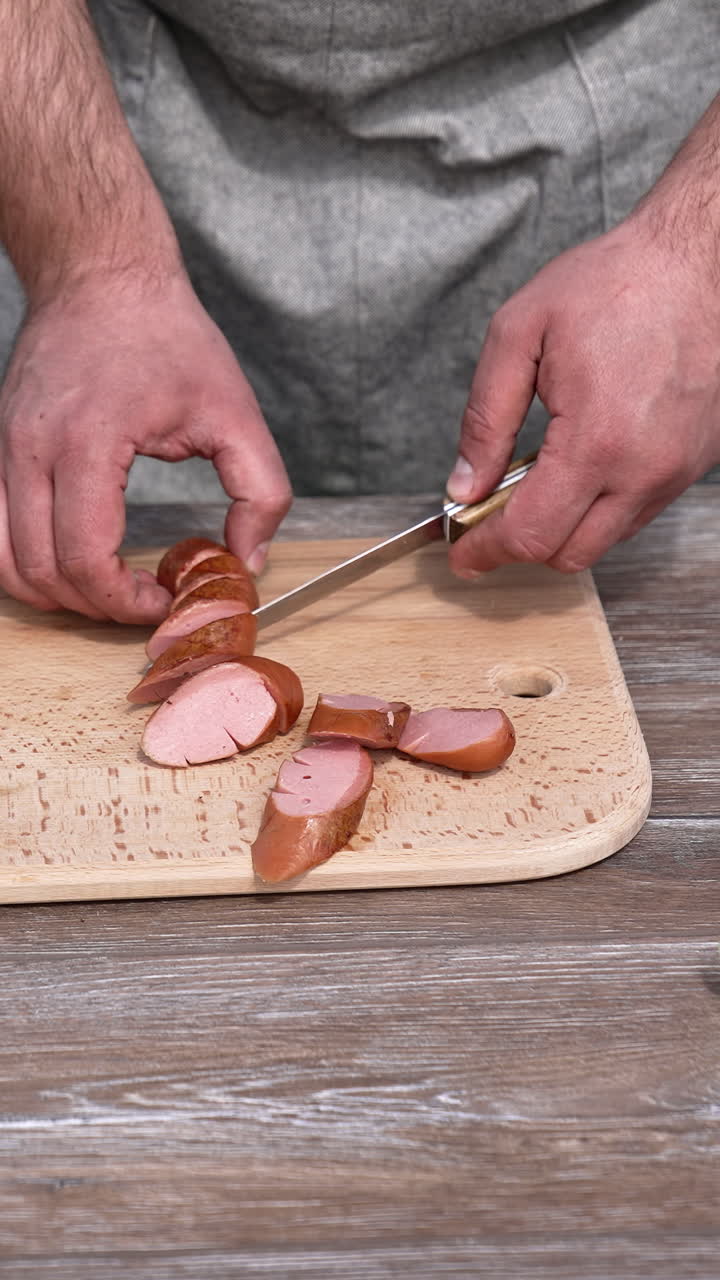Man cutting barbeque sausage for picnic. Tasty lunch at grill outside. Vertical video