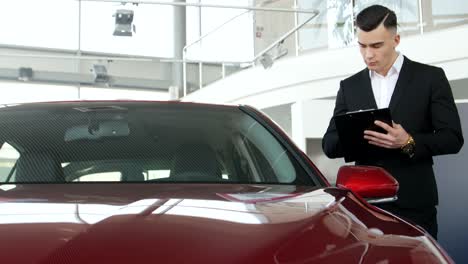 hombre inspeccionando un coche en una sala de exposiciones