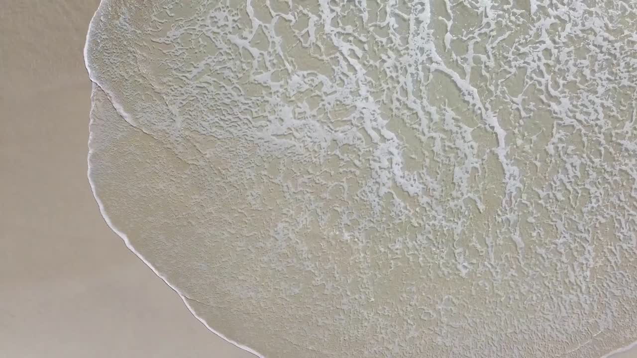 잔잔한 파도가 조용한 해변을 감싸는 공중 조감도