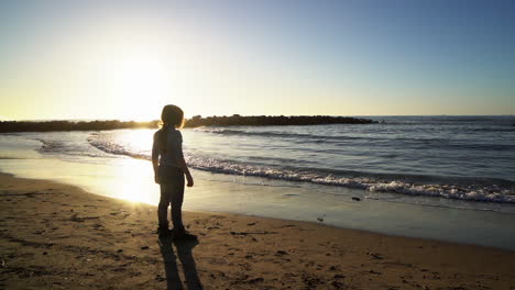 niña pelirroja en la playa mira el océano