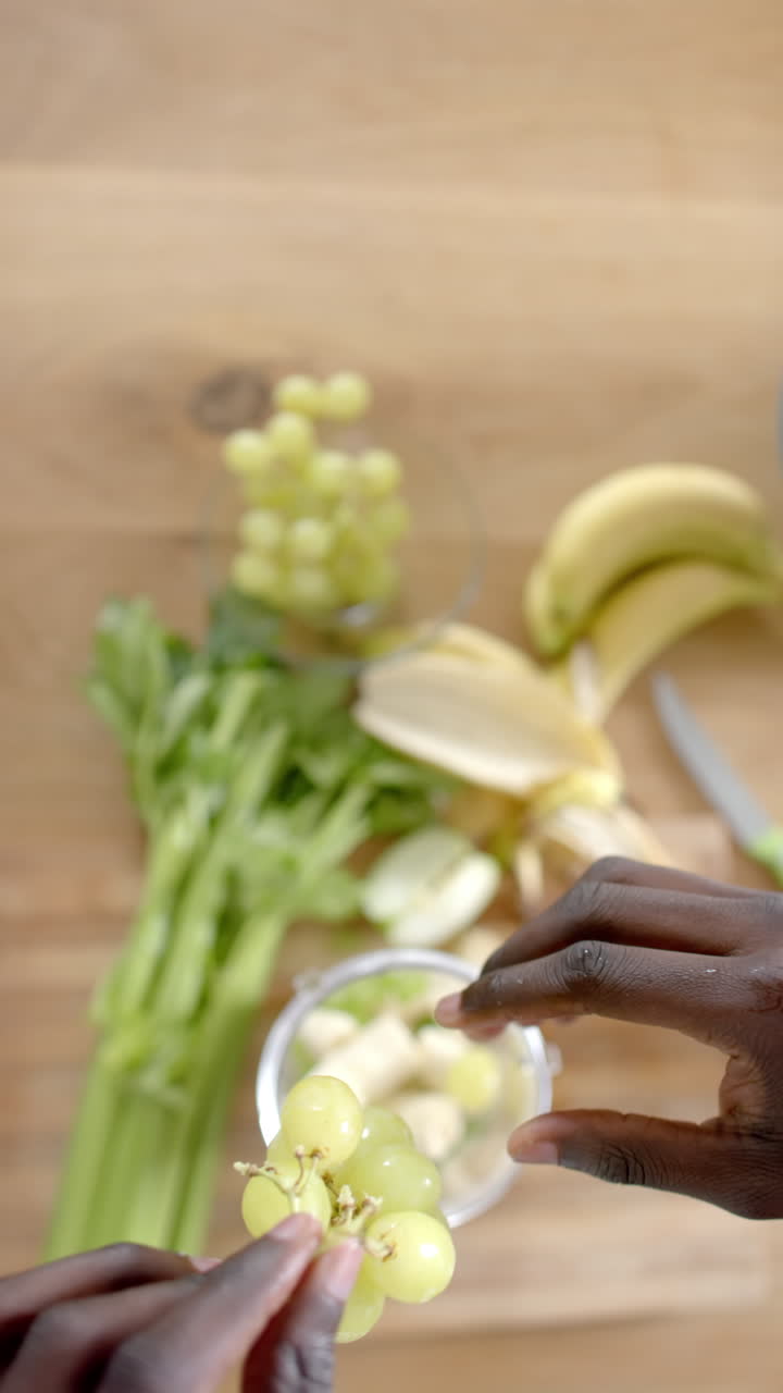 Vertical video of midsection of african american man cleaning waste in kitchen, slow motion
