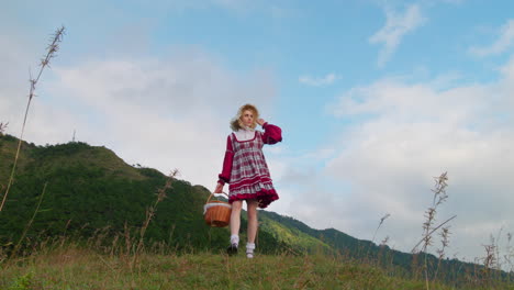 Antigua-Ropa-Medieval-Renacentista-Modelo-Femenino-Mujer-Sosteniendo-Una-Canasta-De-Comida-Mientras-Camina-Sola-En-Cámara-Lenta-En-El-Campo-De-Hierba-Vista-De-ángulo-Bajo