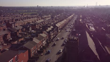 Aerial-orbiting-view-establishing-rows-of-Victorian-terraced-townhouse-community-with-a-long-road-leading-towards-town-centre-at-sunrise