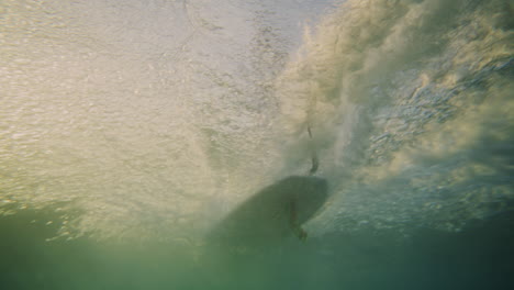 single fin longboard glides across wave at sunrise, view underwater