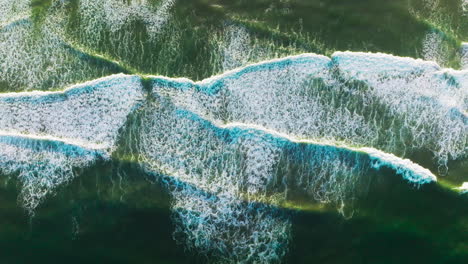 beautiful relaxing movement of foamy waves on the surface of ocean. descending drone footage over the deep green waters.