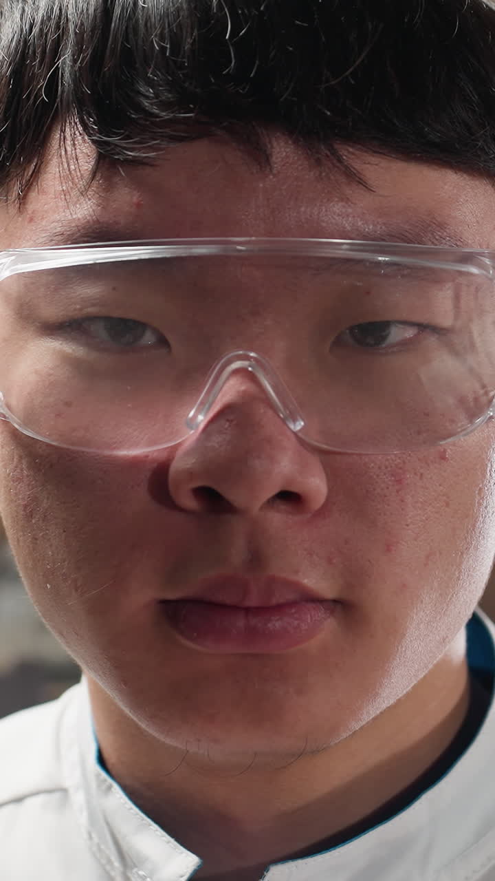 técnico de laboratorio con gafas de protección parpadea los ojos en el taller mecánico, el fondo presenta herramientas industriales, iluminación brillante y maquinaria