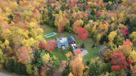 countryside house surrounded with forest in autumn foliage colors, aerial view, smugglers notch, vermont usa