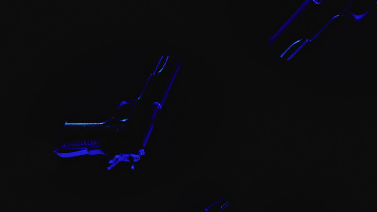 Pistols on the dark background and in blinking red and blue lights are falling in slowmotion