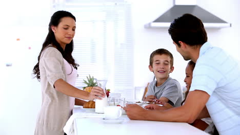 mother pouring milk at family breakfast