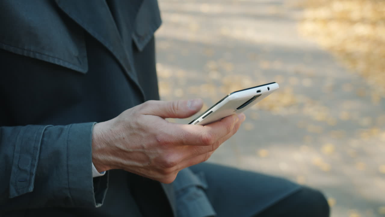 Man using smartphone outdoors in autumn park