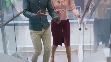 Diverse-business-people-discussing-with-tablet-and-walking-in-creative-office