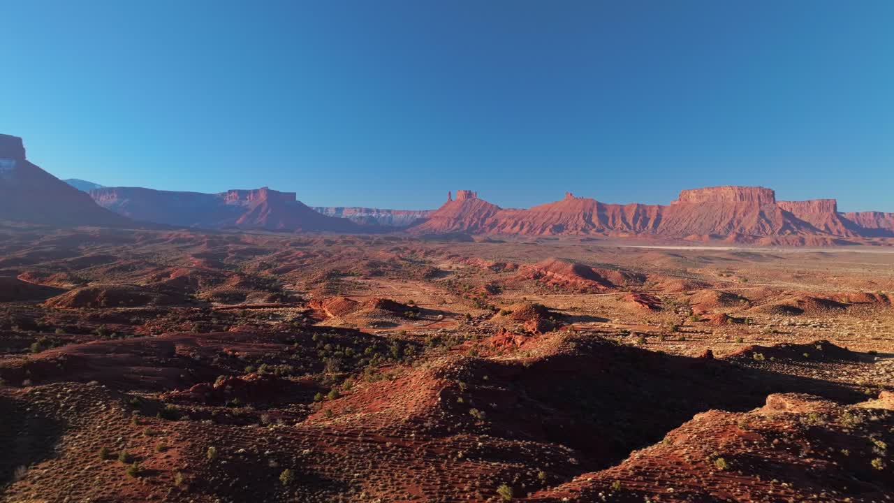 Aerial establishing tracking right of Moab red rock formations, with expansive desert stretching beyond, no people