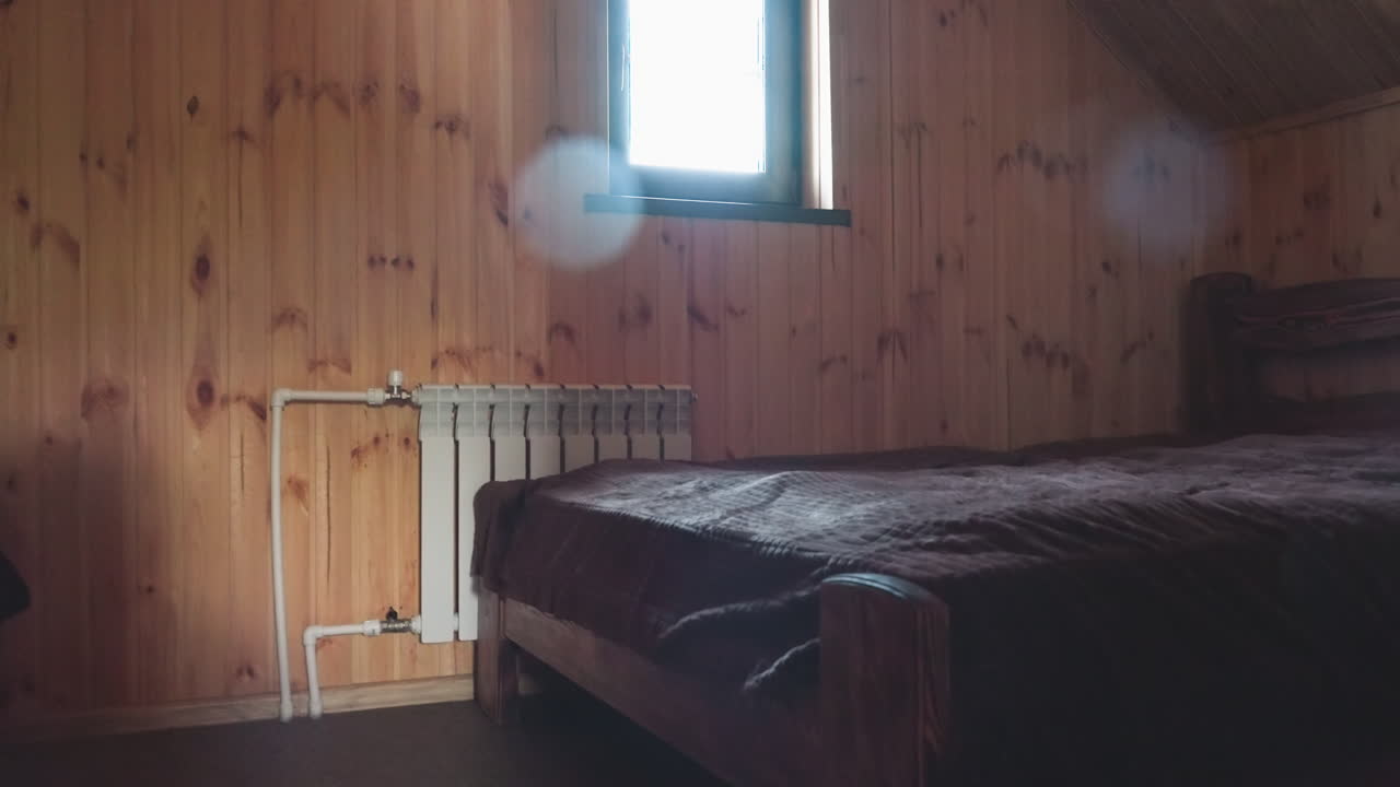 Close up of wood paneled room featuring small rectangular window framing bright light, showcasing vertical panel grain, warm natural tones, and cozy ambient shadows in rustic interior atmosphere