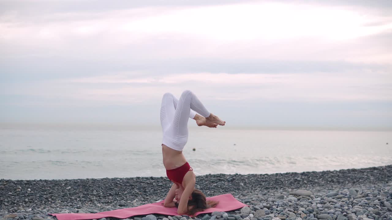 Donna che fa la verticale yoga sulla spiaggia