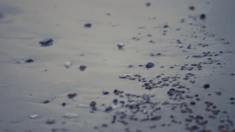 tiempo de la noche macro agua chocando en la playa con hermosas piedras pequeñas