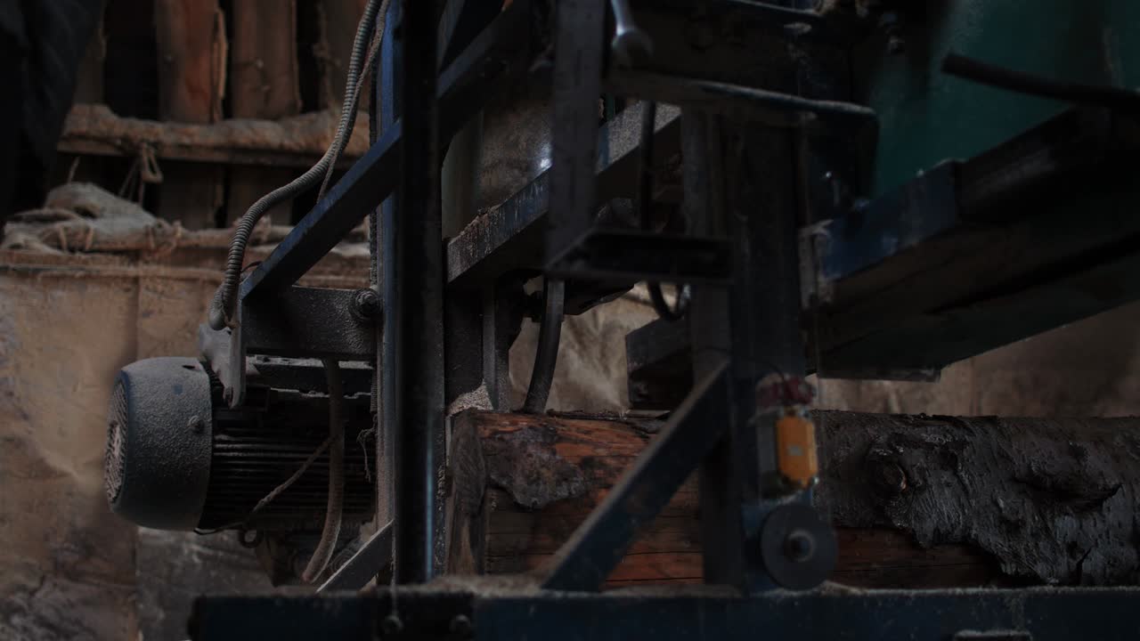 기 기계는 긴 작업 벤치에 누워있는 큰 나무를 잘라 니다.