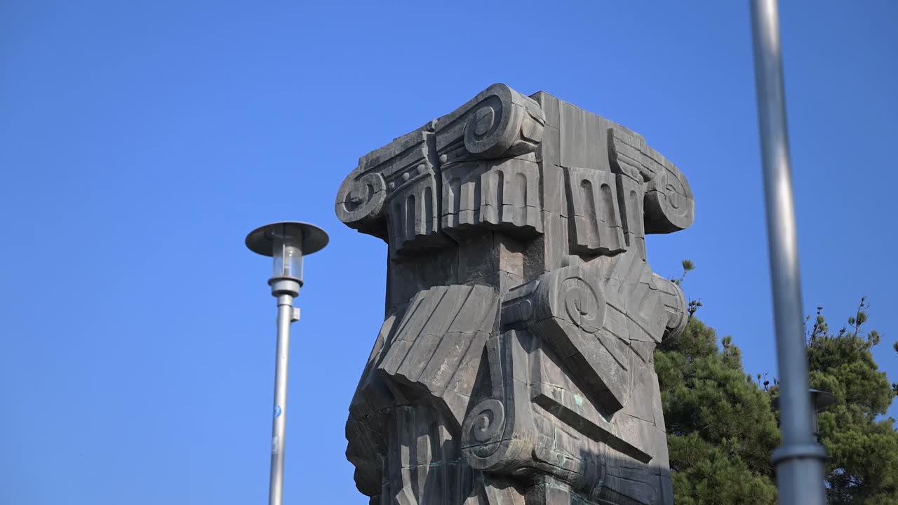 A detailed look at one of the towering pillars at the Chronicle of Georgia, showcasing its intricate carvings and dramatic presence