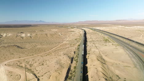 long freight train on tracks crossing desert landscape in nevada, usa