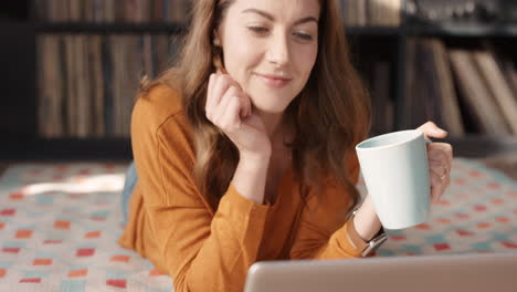 cool woman laughing at funny streaming movie on laptop at home drinking coffee