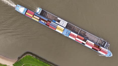 aerial view of a long cargo ship carrying containers on a river