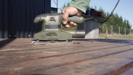 man using a sanding machine on a deck