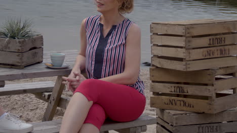 Woman-sitting-on-bench-at-the-beach-and-nodding