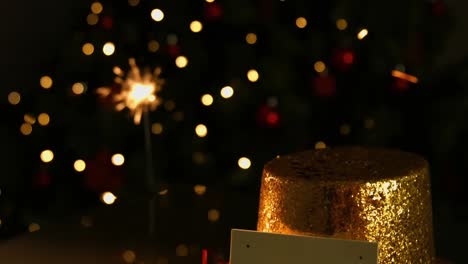 Animation-of-sparkler-and-christmas-hat-and-card-with-copy-space-over-orange-spots-of-light