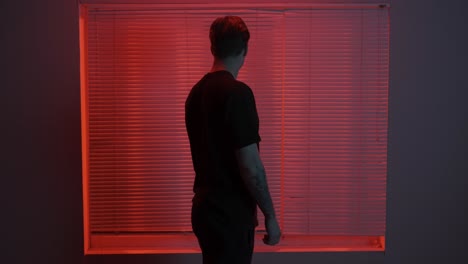 man looking out window in red light