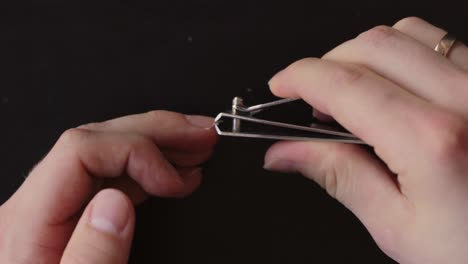 white hands clipping finger nails with metal nail clipper