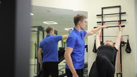 personal trainer assisting woman with exercise in gym