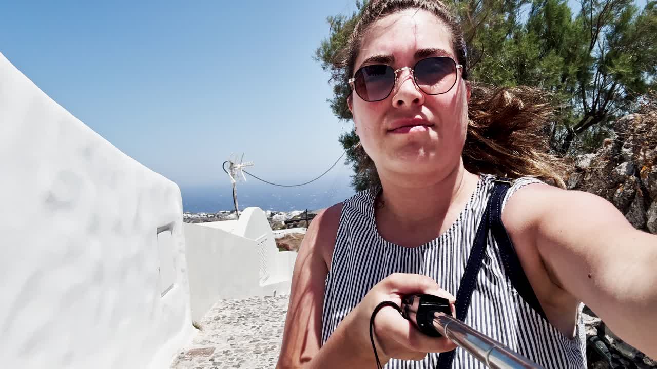 Young tourist woman taking selfie video in santorini, greece