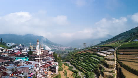 Hillside-town-settlement-with-decorative-mosque-in-mountainous-agricultural-valley