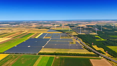 solar panels accumulating sunlight in the countryside. wind farms produce clean energy at backdrop. aerial view