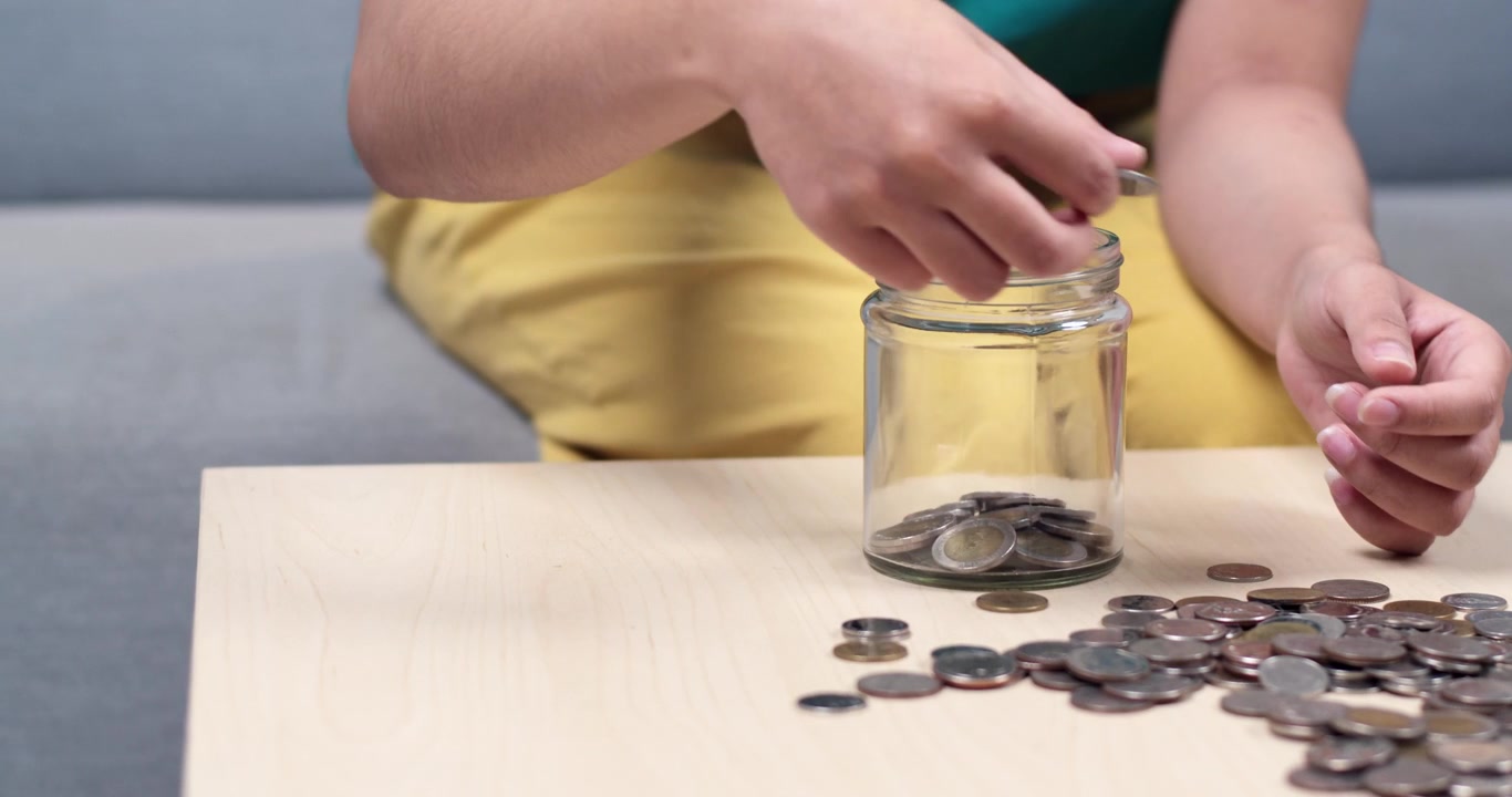 A child learns importance of saving money by collecting coins in a jar fostering financial habits.