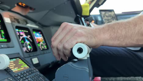 close view inside a jet cockpit while copilot is handling thrust levers and control wheel