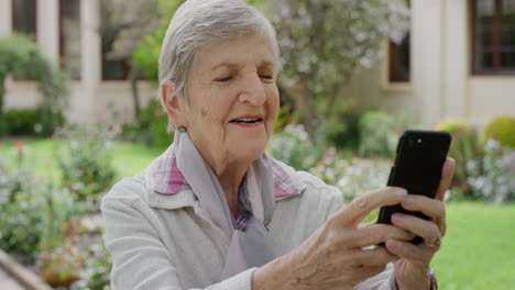 Porträt-Einer-Glücklichen-älteren-Frau,-Die-Ihr-Smartphone-Benutzt-Und-Im-Gartenhintergrund-Ein-Foto-Mit-Einer-Handykamera-Macht