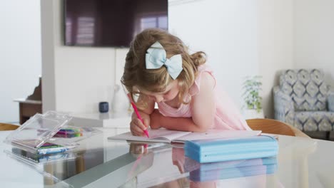 chica caucásica dibujando en un cuaderno en la sala de estar