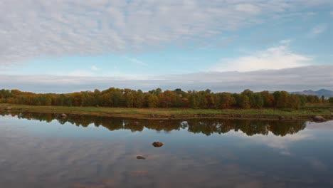 serene view of a calm river reflecting autumn trees in vestarelen, norway