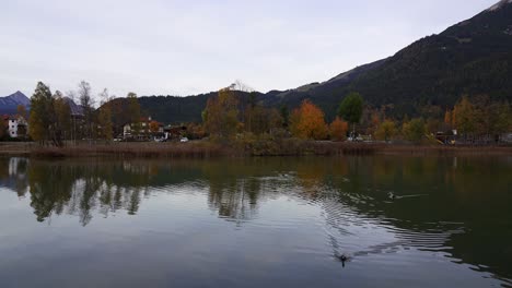 Langsame-Schwenkaufnahme-Eines-Sees-In-Den-Alpen-Im-Herbst-Mit-Berghintergrund