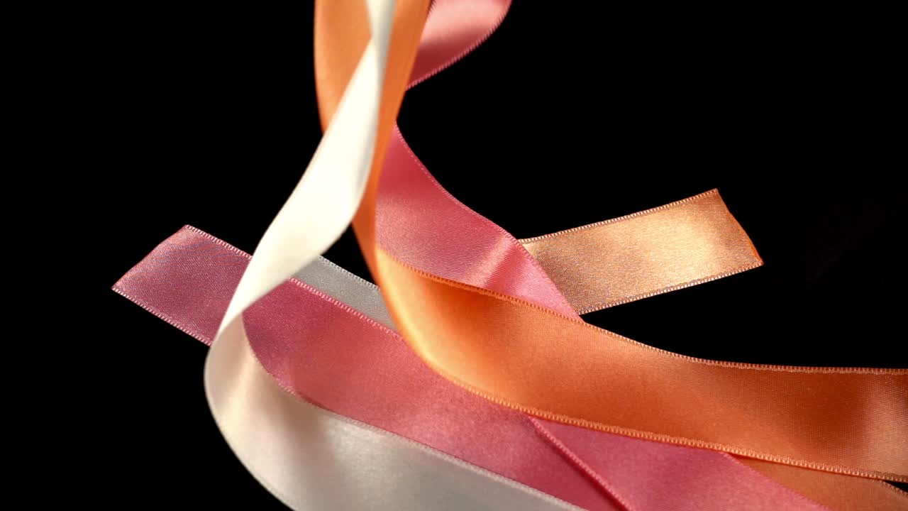 Satin ribbon on a black background. Slow motion