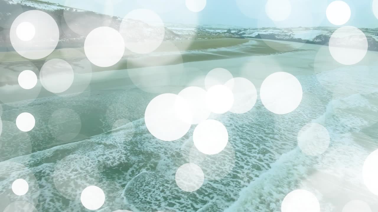 Translucent bokeh drifting over aerial shoreline, central glow sparking accumulation to veil surf